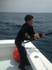 boy on boat with fishing pole in ocean