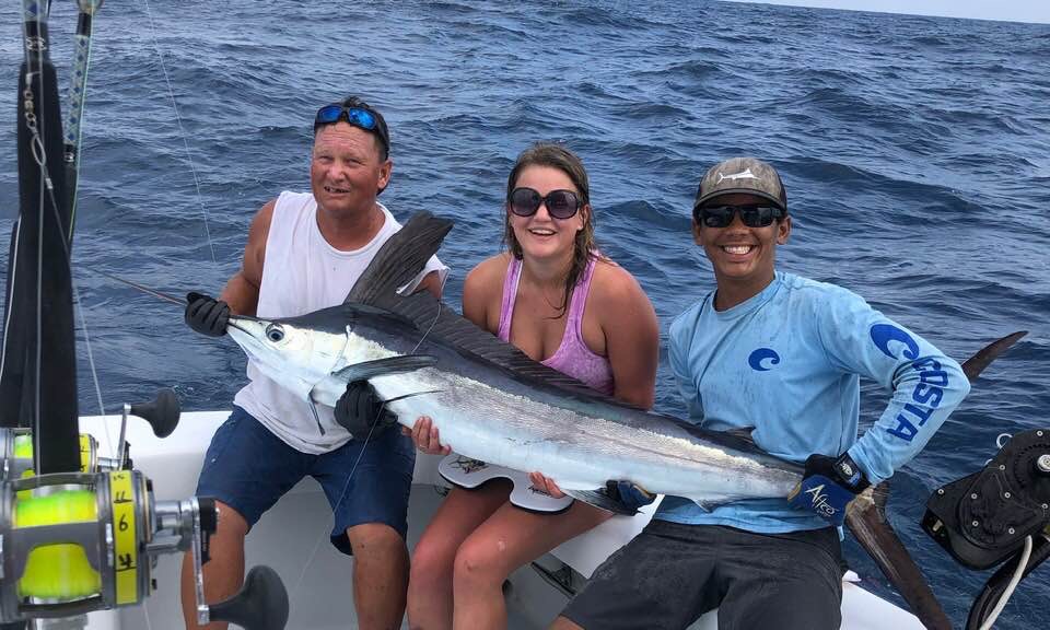3-people-holding-swordfish-on-edge-of-boat